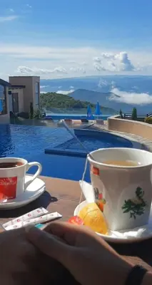 a person holding a cup of coffee and a plate of food at Eagle View Milmari N81 in Kopaonik