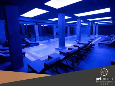a row of lounge chairs in a building with a pool at Apartman PETICA KOP A8 Kopaonik in Kopaonik