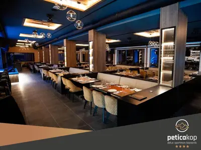 a restaurant with a long bar with tables and chairs at Apartman PETICA KOP A8 Kopaonik in Kopaonik