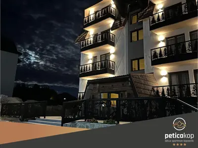 a large white building with balconies at night at Apartman PETICA KOP A8 Kopaonik in Kopaonik