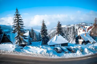 a snow covered village with cars parked in the snow at Mujen Lux Tutic - Free Spa & Wellness in Kopaonik