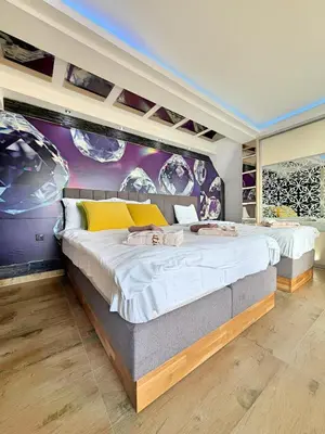 a bedroom with a large bed with a purple wall at Mujen Lux Tutic - Free Spa & Wellness in Kopaonik