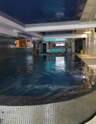a large swimming pool in a hotel lobby at Apart Hotel & spa Zoned II, Kopaonik, apartman Lukač - special benifit Children up to 17 of age accompanied by two adutls staj for free! FREE PARKING! in Kopaonik