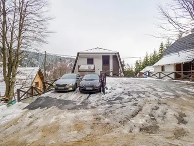 two cars parked in front of a house in the snow at Apartmani Šišarka in Kopaonik
