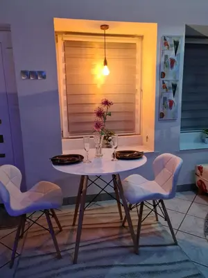a table with chairs and a vase with flowers on it at Apartman -HARMONY- in Paraćin