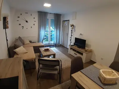 a living room with a couch and a clock on the wall at Ajrin Apartman Kopaonik in Kopaonik