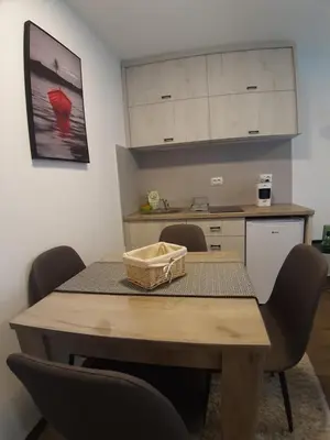 a dining room table with chairs and a kitchen at Ajrin Apartman Kopaonik in Kopaonik