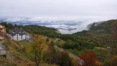 a house on a hill in a valley with clouds at Apartman Lorena N70a in Kopaonik