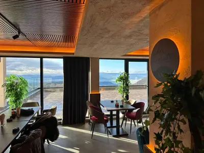 a room with a table and chairs and large windows at Apartman Lorena N70a in Kopaonik