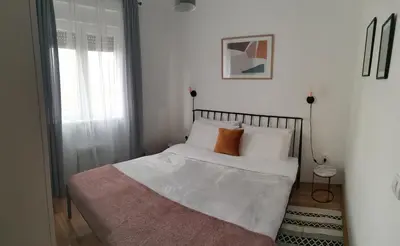 a bed with white sheets and orange pillows in a bedroom at Apartman Kardaš in Vrnjačka Banja