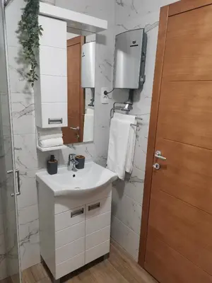 a white bathroom with a sink and a mirror at Apartman Kardaš in Vrnjačka Banja