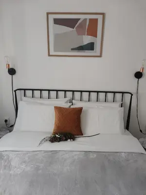 a bed with white pillows and a picture on the wall at Apartman Kardaš in Vrnjačka Banja
