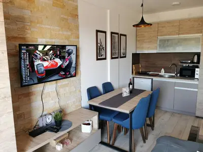a kitchen with a table and a tv on a wall at SkyKop Apartman L21 in Kopaonik