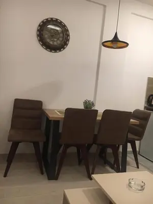 a dining room table with chairs and a clock on the wall at Apartman “N 17”Milmari-Kopaonik in Kopaonik