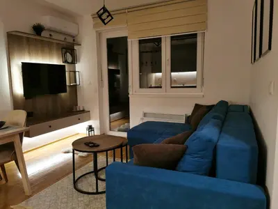 a living room with a blue couch and a television at Apartman Maximus in Vrnjačka Banja