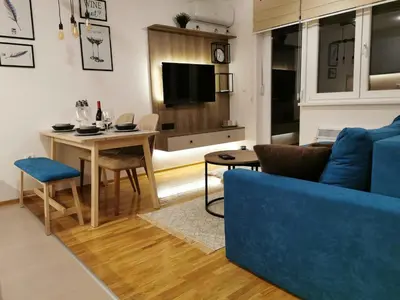 a living room with a blue couch and a table at Apartman Maximus in Vrnjačka Banja