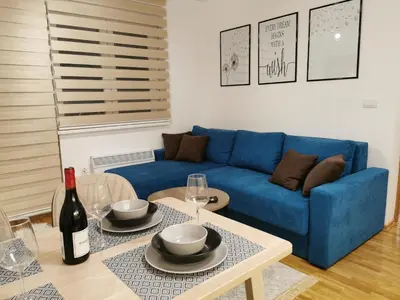 a living room with a blue couch and a table at Apartman Maximus in Vrnjačka Banja