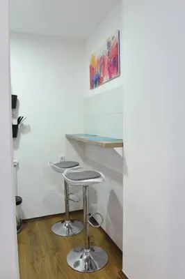 a desk with two stools in a room at Central Apartment in Ćuprija