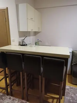 a kitchen with a bar with four chairs around it at Apartmani Nedeljkovic Brzece Kopaonik in Brzeće