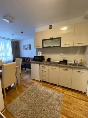 a kitchen with white cabinets and a living room at Apartments Enzo Kopaonik in Kopaonik