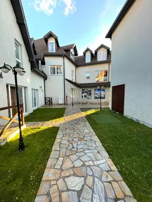 a house with a stone walkway in front of a yard at Apartments Enzo Kopaonik in Kopaonik