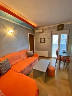 a living room with an orange couch and a table at Apartman Marko B in Vrnjačka Banja