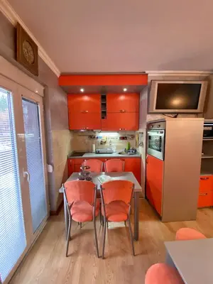 a kitchen with orange cabinets and a table and chairs at Apartman Marko B in Vrnjačka Banja