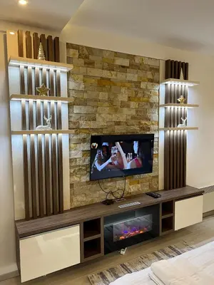 a living room with a tv on a stone wall at Apartman Holiday in Kopaonik