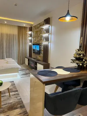 a living room with a dining table and a living room with a couch at Apartman Holiday in Kopaonik