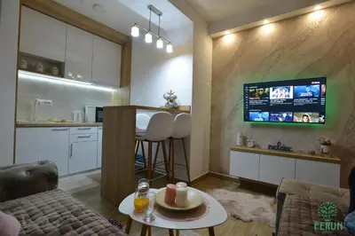 a living room with a kitchen and a tv on the wall at PERUN in Vrnjačka Banja