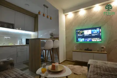 a living room with a kitchen and a tv on a wall at PERUN in Vrnjačka Banja