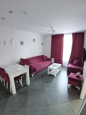 a living room with a red couch and a table at Wolf Apartments Kopaonik in Kopaonik