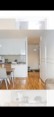 a kitchen with white cabinets and a wooden floor at Wolf Apartments Kopaonik in Kopaonik