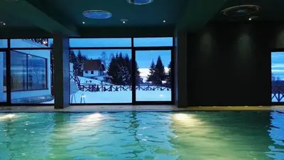 an indoor swimming pool with a view of a house at Wolf Apartments Kopaonik in Kopaonik