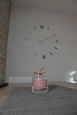 a candle sitting on a rug in front of a clock at Apartman Ema BIG 64m2-duplex Kopaonik in Kopaonik