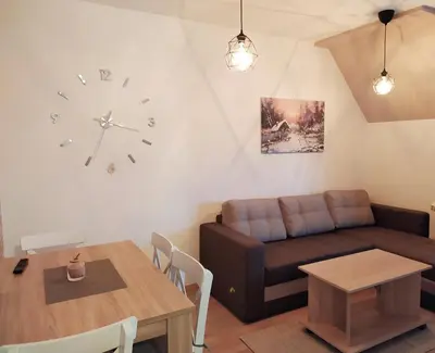 a living room with a couch and a clock on the wall at Apartman Ema BIG 64m2-duplex Kopaonik in Kopaonik