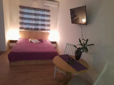 a small bedroom with a bed and a table at V & V Studio Apartments in Niš