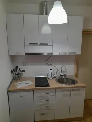 a kitchen with white cabinets and a sink and a lamp at V & V Studio Apartments in Niš