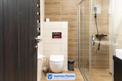 a bathroom with a toilet and a glass shower stall at Sunčana Planina - Apartmani Wombat in Kopaonik