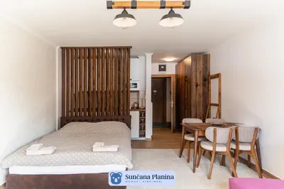 a bedroom with a bed and a table and chairs at Sunčana Planina - Apartmani Wombat in Kopaonik