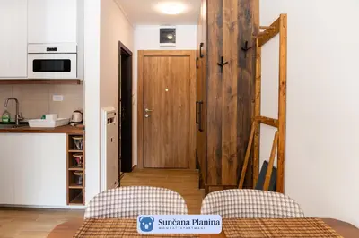 a kitchen with a wooden door and two chairs at Sunčana Planina - Apartmani Wombat in Kopaonik