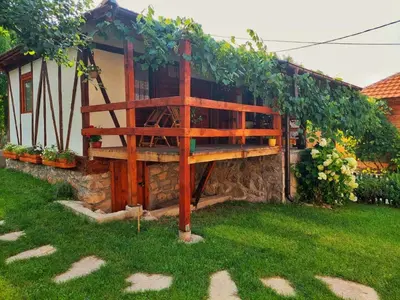 a wooden bench sitting in the grass next to a house at Mitrović in Boljevac
