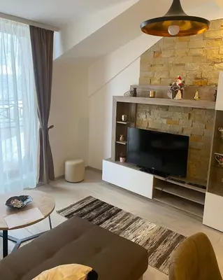 a living room with a television and a stone fireplace at Milmari Apartman N92 Kopaonik in Kopaonik