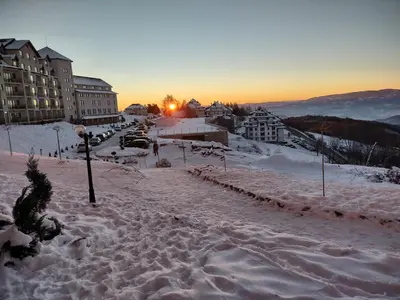 a snow covered street with the sun setting in the background at MILMARI Kop N10 in Kopaonik