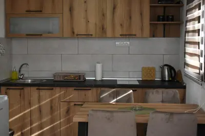 a kitchen with wooden cabinets and a table with chairs at Vikendica Čeperković #3 in Kopaonik