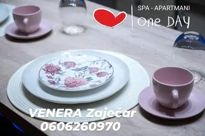 a table with two cups and a plate with flowers on it at Spa Apartman URBAN Life ZAJEČAR in Zaječar