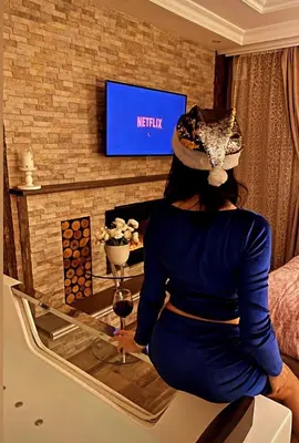 a woman sitting in front of a tv with a glass of wine at Spa Apartman URBAN Life ZAJEČAR in Zaječar