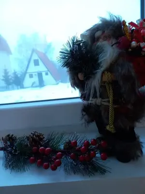 a santa claus doll sitting on a window sill with christmas decorations at KopStar Apartment Kopaonik G2 in Kopaonik