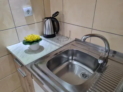 a kitchen sink with a vase of yellow flowers on a counter at ZVEZDA LUX in Kruševac
