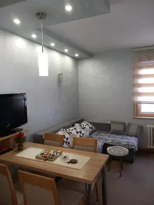 a living room with a table and a couch and a room with a bed at Apartmani Dušica Konaci Kopaonik in Kopaonik